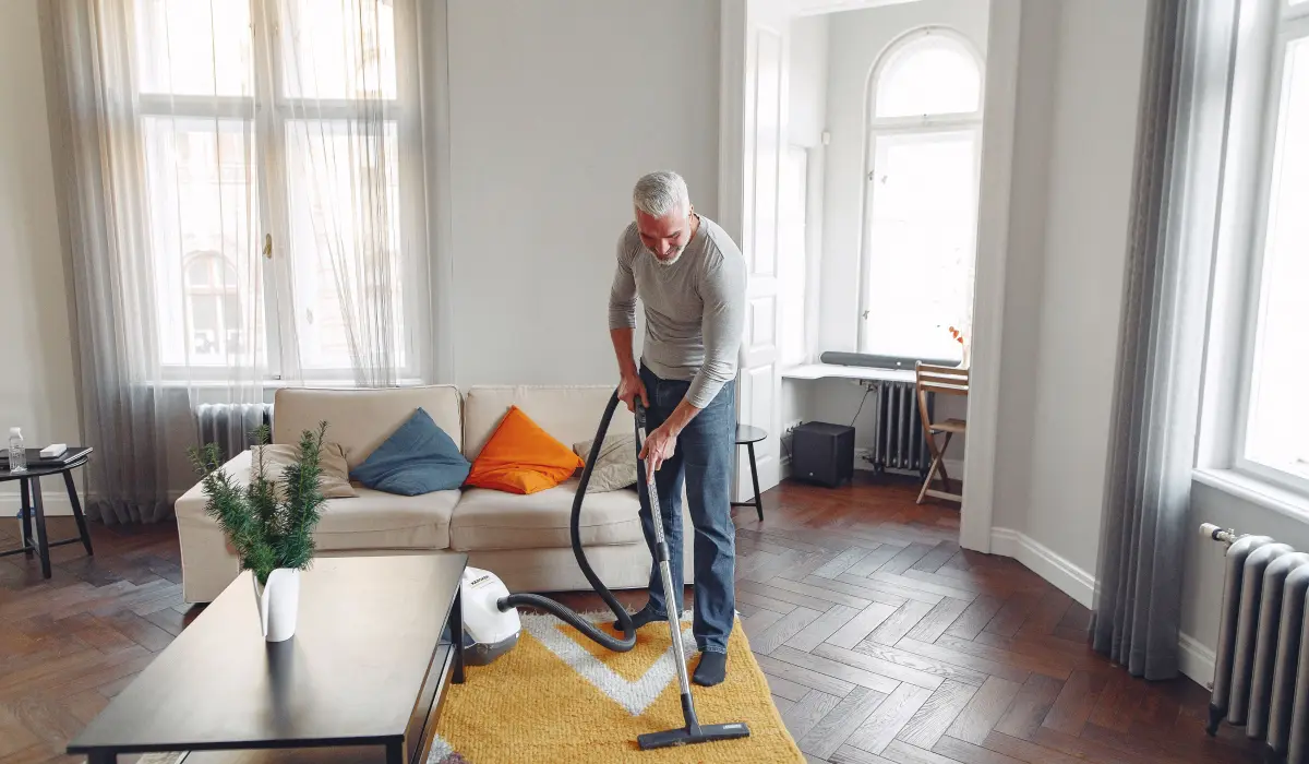 Mann reinigt einen Teppich in seinem Wohnzimmer